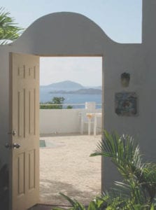 A door open to the patio with a view of the ocean.