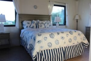 A bed with blue and white sheets in front of a window.