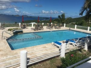 A pool with chairs and umbrellas in the background.