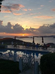 A pool with chairs and tables in the foreground.