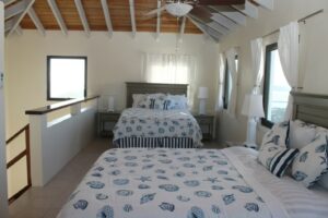 A bedroom with two beds and a large window.